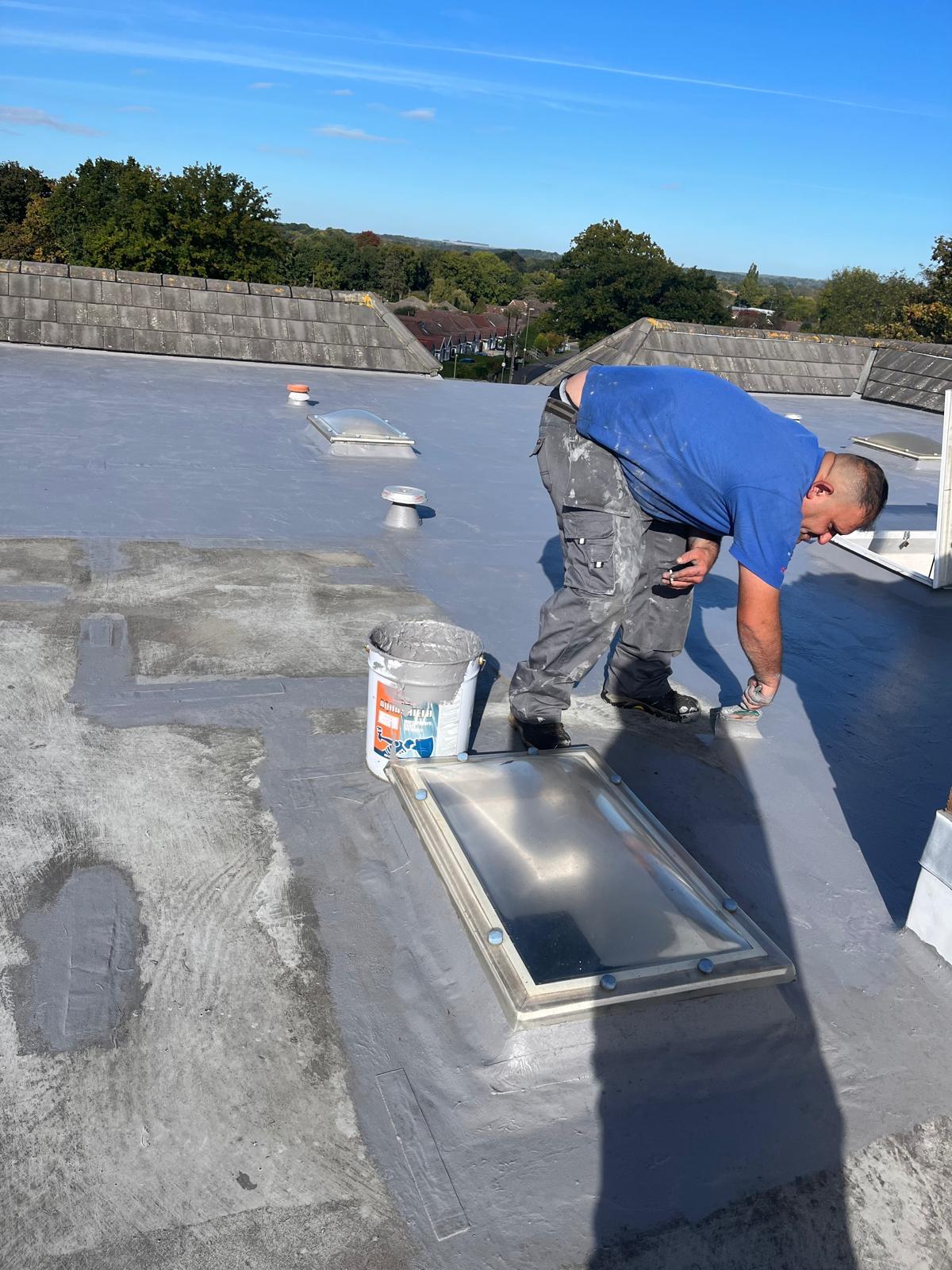 Roofer finishing a flat roof around a roof light